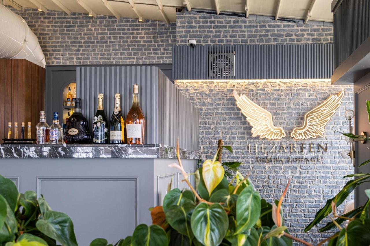 Cvk Park Bosphorus Hotel Istanbul Exterior photo The photo shows a stylish bar area with a modern design. The bar features a marble countertop and is lined with various bottles of alcohol, including spirits and champagne. Behind the bar, there is a decorative wall made of gray bricks, and a promine