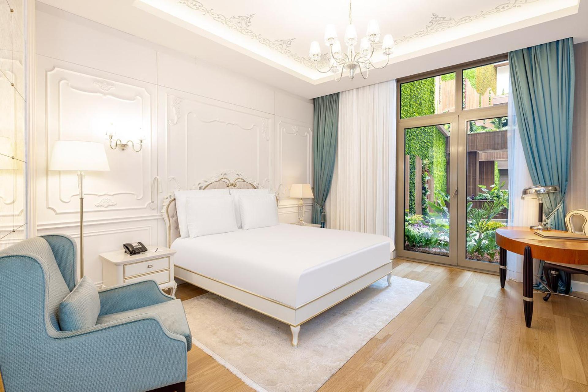 Cvk Park Bosphorus Hotel Istanbul Exterior photo The photo shows a well-decorated bedroom. It features a spacious, light-filled design with white walls that have ornate detailing. The room includes a large, unmade bed with a simple white mattress and a light-colored bed frame. Next to the bed is a 