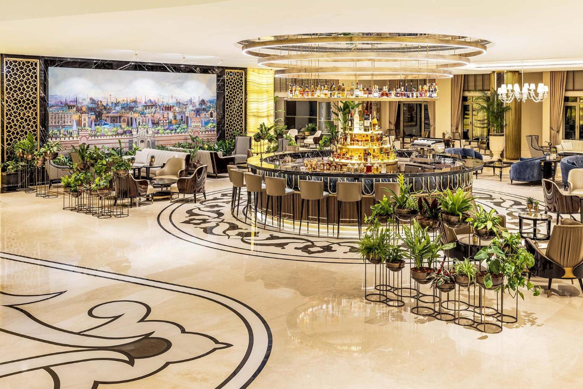 Cvk Park Bosphorus Hotel Istanbul Exterior photo The photo shows a luxurious interior of a hotel lobby or lounge area. In the center, there is an elegant circular bar surrounded by high-backed chairs. The floor features intricate designs, and there are lush green plants scattered throughout the spa
