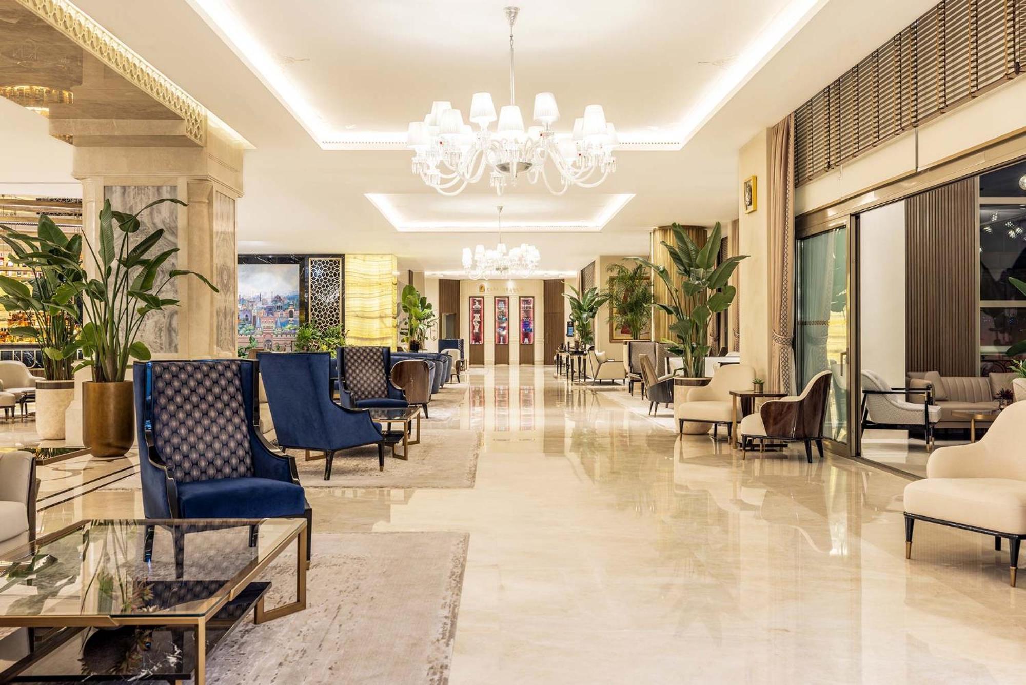Cvk Park Bosphorus Hotel Istanbul Exterior photo The photo depicts a spacious and elegantly designed lobby area. The floor is made of polished marble, giving a luxurious feel. There are several seating areas with stylish chairs, some of which are upholstered in blue fabric with geometric patterns, 