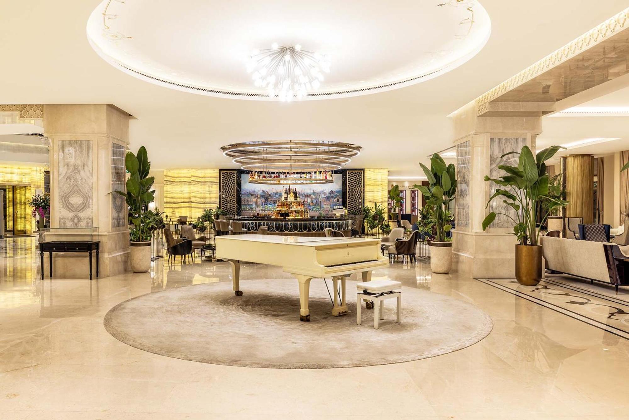 Cvk Park Bosphorus Hotel Istanbul Exterior photo The photo shows an elegant interior space, likely a hotel lobby or a luxurious lounge. In the center, there is a grand white piano on a circular rug, surrounded by a polished floor. The ceiling features a large, contemporary chandelier that adds to t