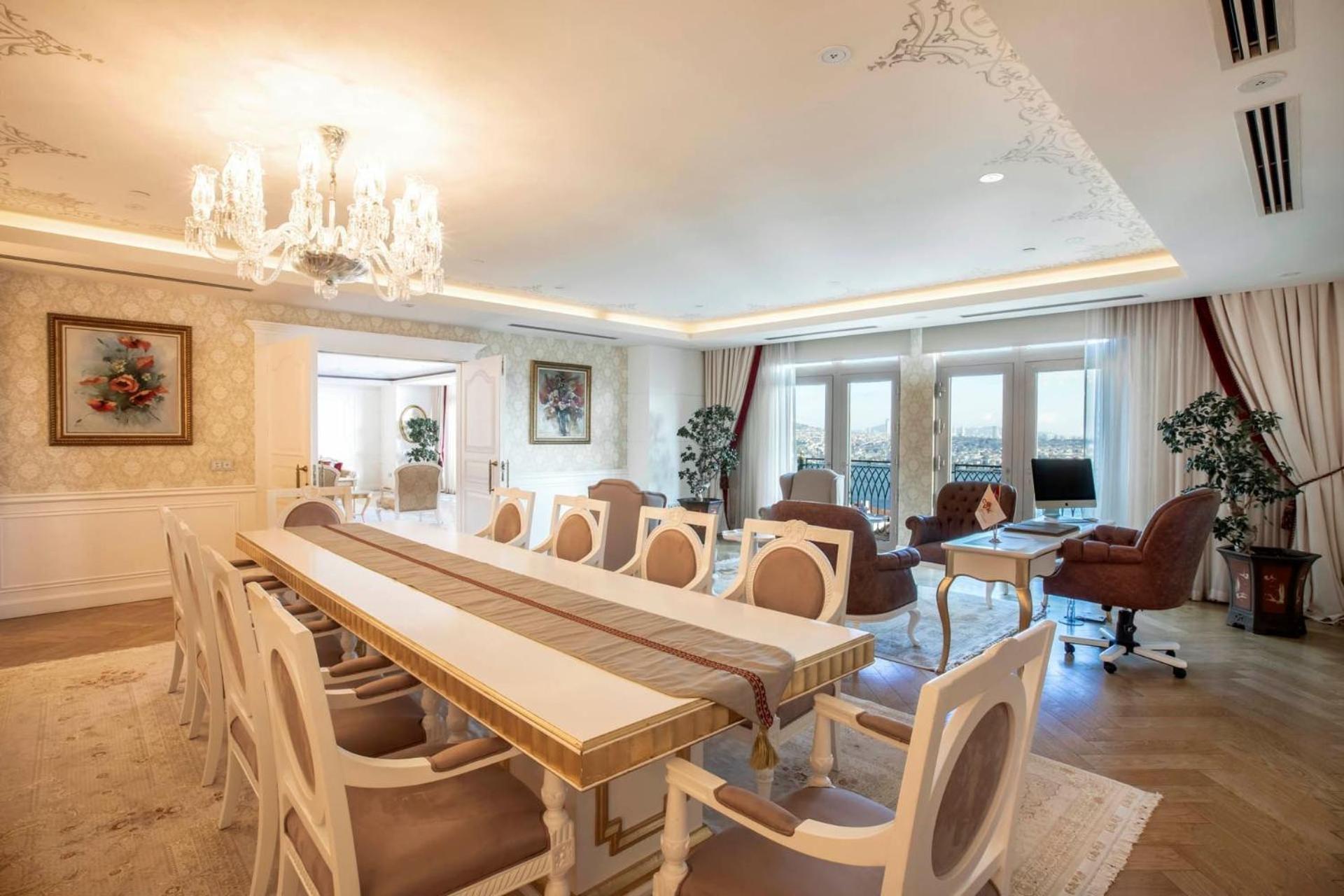 Cvk Park Bosphorus Hotel Istanbul Exterior photo The photo shows an elegant dining room or meeting space. It features a long rectangular table surrounded by several styled chairs, all arranged on a light-colored rug. The decor includes a chandelier hanging from the ceiling and large windows that al