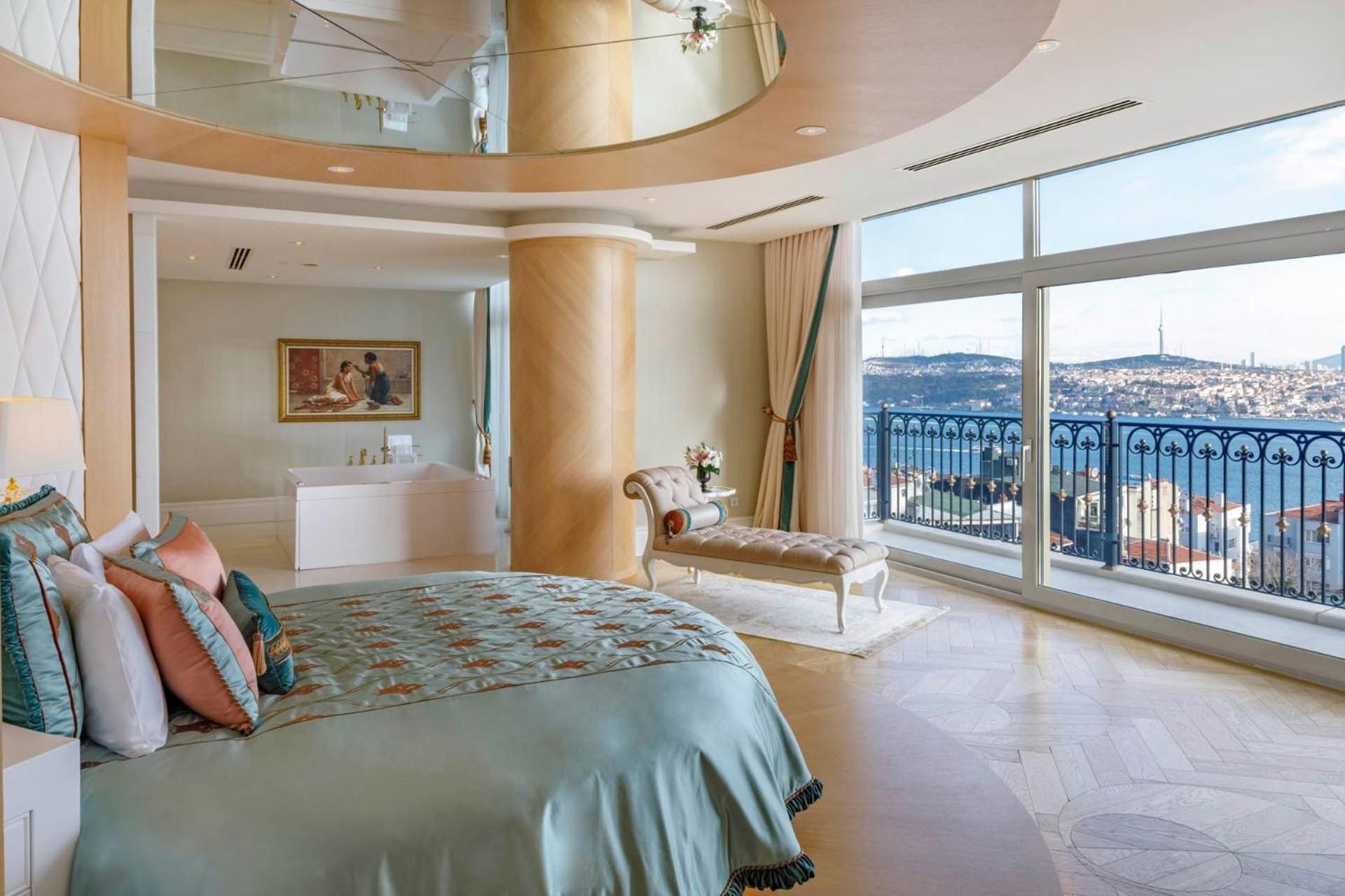 Cvk Park Bosphorus Hotel Istanbul Exterior photo The photo shows a luxurious bedroom with a spacious and modern design. It features a large bed with a decorative quilt and several pillows in soft colors. There is a comfortable seating area with a bench near the window, which offers a stunning view 